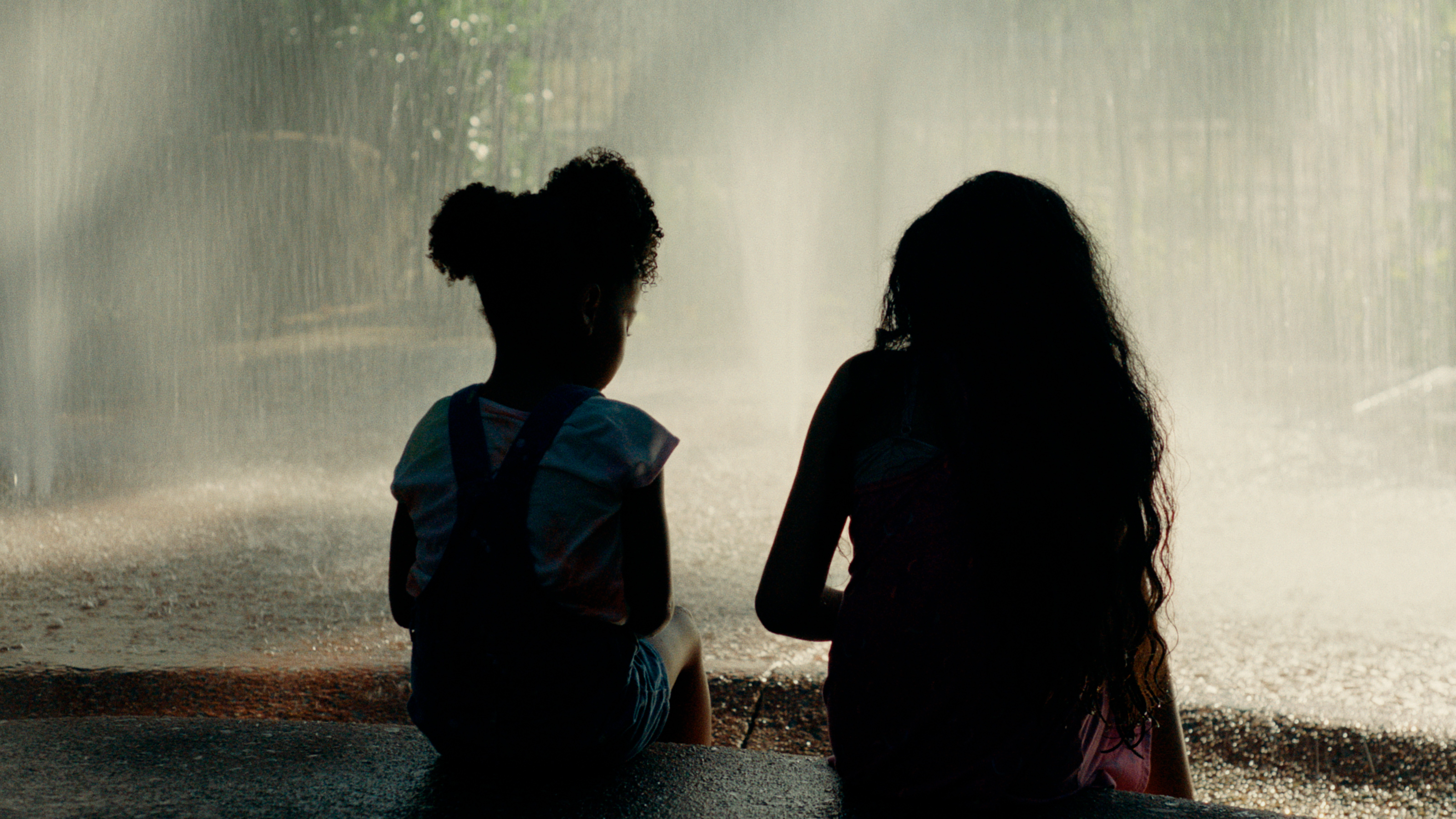 Two young girls sitting solemnly by a fountain